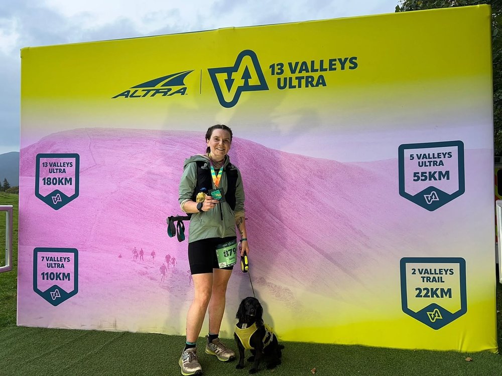 Kate with her medal and dog at the 13 Valleys Ultra finish