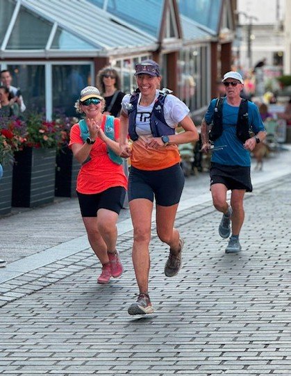 Sam running through the streets of Keswick with her support team at the finish of the Bob Graham Round